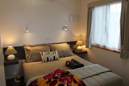 VentnorOMARU FARM STAY的一间卧室配有一张带两盏灯的床和一扇窗户。