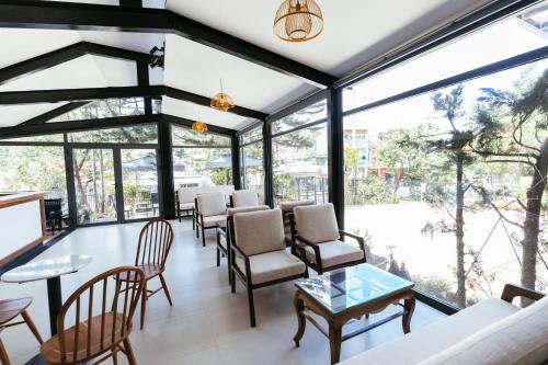 大叻Minh Chi Hotel的客房设有窗户、椅子和桌子。