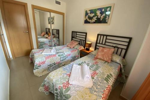 韦尔瓦Apartamento Playa Marina Particular Isla Canela的一间卧室配有两张床和镜子