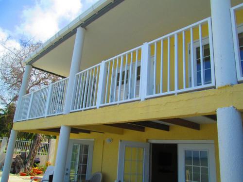 圣安德烈斯Haynes Cay View的黄色房屋的阳台,带白色栏杆