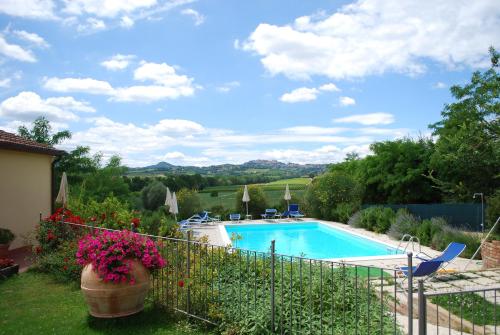 蒙特普齐亚诺伊尔坎塔斯托里农家乐的一座带鲜花和围栏的庭院内的游泳池