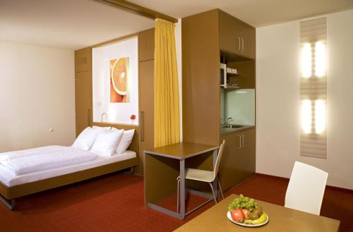 维也纳新城橙色翅膀维也纳新城酒店的酒店客房,配有一张床和一张桌子,还有一碗水果