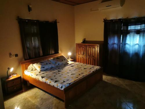 科托努ROMO house的一间卧室配有床和两个带窗帘的窗户