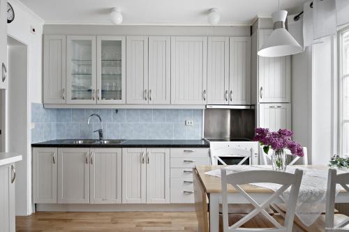 哈诺桑德Centrala lägenheter med allt som behövs!的厨房配有白色橱柜和紫色花卉桌