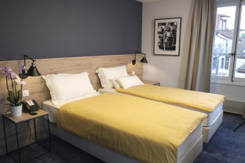 伯尼安Boutique Hôtel de l'Ecu Vaudois的配有黄色床单的酒店客房的两张床