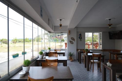 埃杰阿巴德Eceabat Doğa Pansiyon-Hotel的餐厅设有桌椅和大窗户。