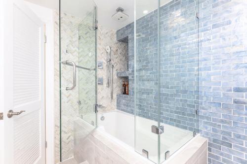 檀香山Waikiki Shore 1116 Beachfront的浴室设有浴缸和蓝色瓷砖淋浴。