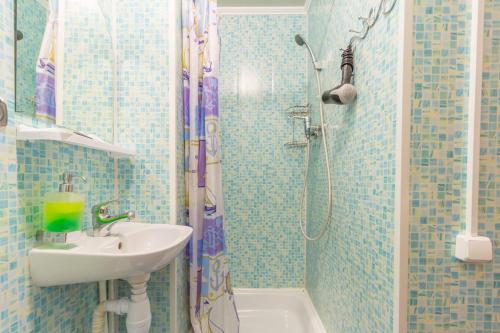 秋明柯洛斯酒店的蓝色瓷砖浴室设有水槽和淋浴