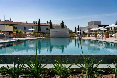 卡塞雷斯阿雷纳莱斯宫殿霍斯皮斯及spa酒店的度假村内的大型游泳池,配有遮阳伞