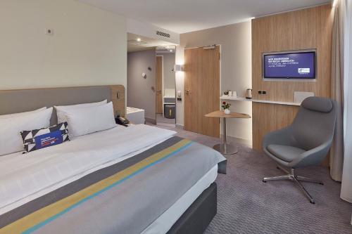 梅尔齐希Holiday Inn Express - Merzig, an IHG Hotel的酒店客房配有一张床、一把椅子和一台电视。