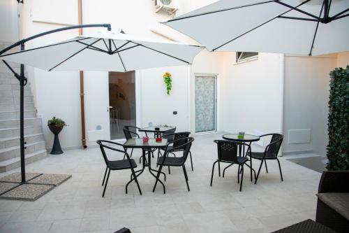 布林迪西Dimora Guerrieri的庭院配有2张桌子和椅子以及遮阳伞。
