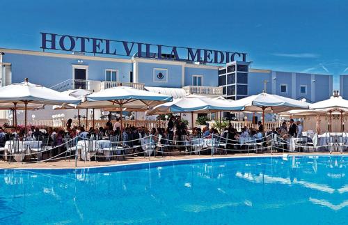 罗卡圣焦万尼美第奇别墅酒店的酒店设有一个大型游泳池,配有桌子和遮阳伞