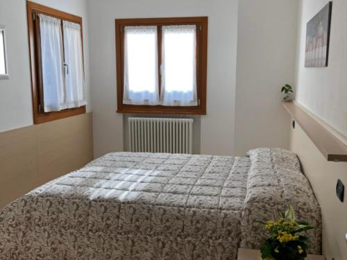 FaverAppartamento Dante Faver Val di Cembra Ospitar的一间卧室设有一张床和两个窗户。