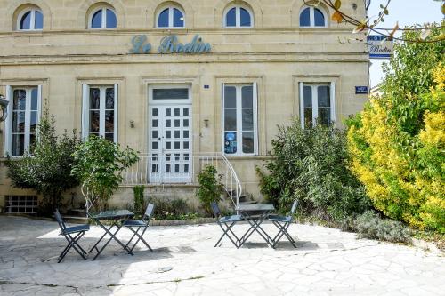 巴扎斯Le Rodin Bazas的前面有两把桌子和椅子的建筑