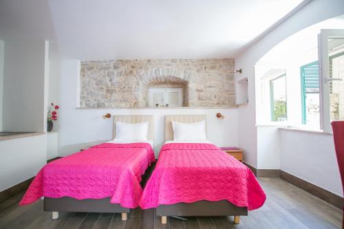 斯普利特Garden Apartment Hotel的卧室内的两张床,配有粉红色的毯子