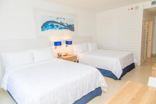 阿卡普尔科阿卡普尔科拉岛假日酒店的配有白色墙壁和蓝色灯具的客房内的两张床