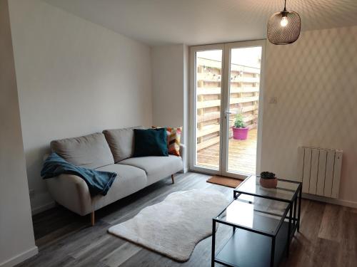 布雷斯特Joli appartement avec jardin-terrasse privé的带沙发和玻璃桌的客厅