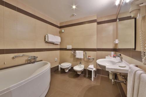 卢卡贝斯特韦斯特桂尼吉大酒店的一间带两个盥洗盆、浴缸和卫生间的浴室
