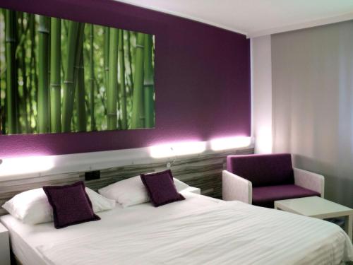 林茨林茨宜必思尚品酒店的一间卧室配有一张床和紫色的墙壁