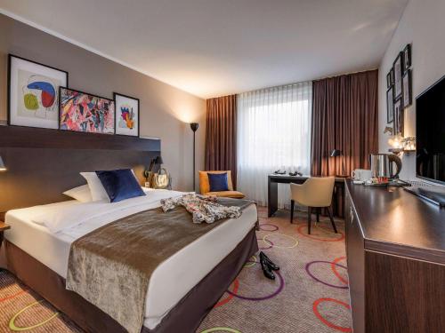 汉诺威汉诺威迈迪卡公园美居酒店的酒店客房设有一张大床和一张书桌。
