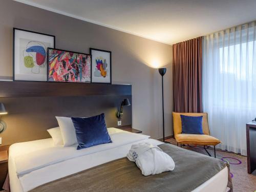 汉诺威汉诺威迈迪卡公园美居酒店的酒店客房带一张大床和一把椅子