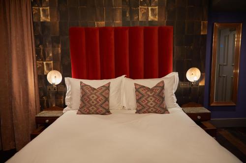 伦敦The Kings Arms Pub & Boutique Rooms的一张带两个枕头和红色窗帘的大床