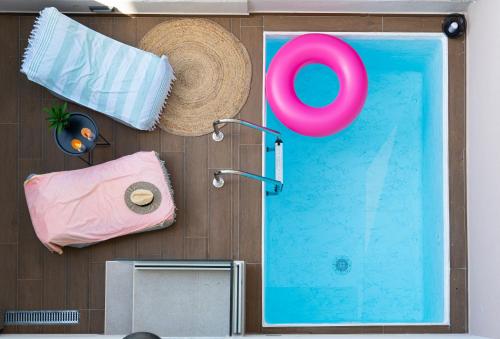 内亚卡瓦里Aelia Seaside Luxury Suites的一个带稻草帽的泳池,泳池旁有毛巾,游泳池