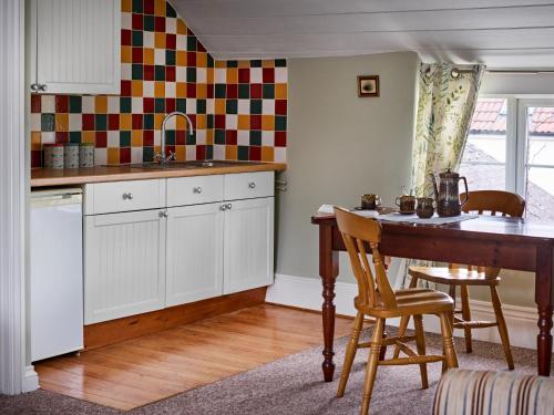 惠灵顿The Martlet Inn的厨房配有白色橱柜和桌椅
