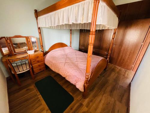 DheriniaLovely house not far from the beach, near Protaras的一间卧室设有一张天蓬床和木地板。