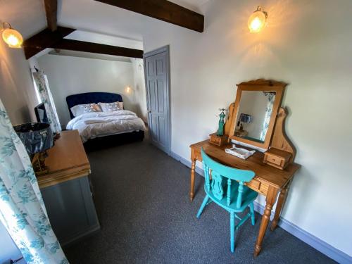North CornellyInglenook Cottage near Porthcawl and Beaches的一间卧室配有书桌、镜子和床
