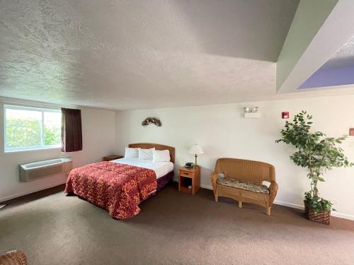 莱昂斯VIBE INN - WHIRLPOOLS SUITES - Lyons的配有一张床和一把椅子的酒店客房