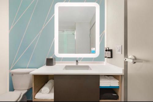 波特兰AVID Hotels Corpus Christi - Portland, an IHG Hotel的一间带水槽、镜子和卫生间的浴室