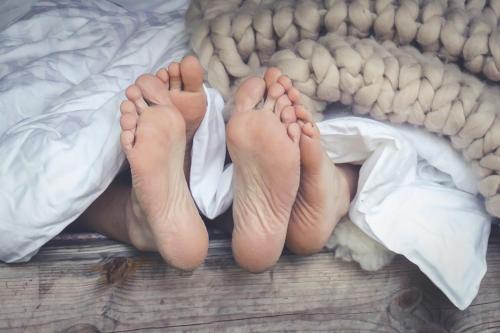 KinnulaKarkausmäen Kammari的躺在床上,脚踩在毯子上的人