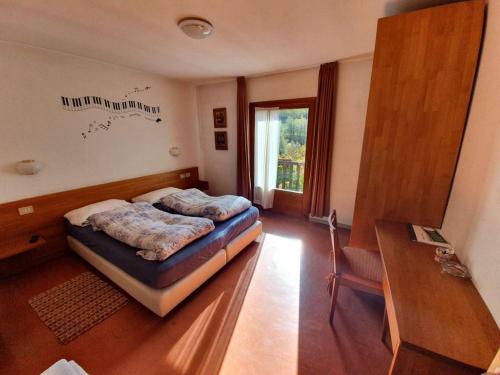 博尔米奥Hotel Daniela的一间卧室配有一张床、一张书桌和一个窗户。