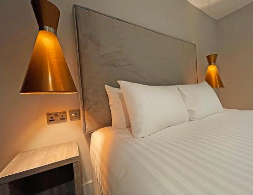 布莱克浦1820 Boutique Rooms & Suites的一间卧室配有一张白色床和两盏灯。