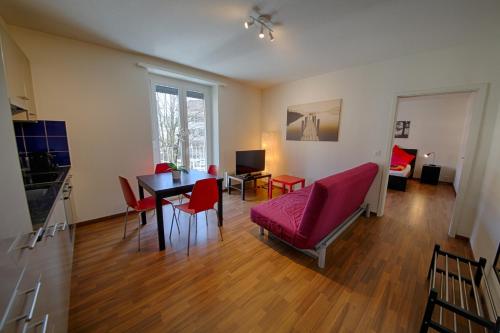 苏黎世HIT欧瑞康出租公寓的客厅配有桌子和红色椅子