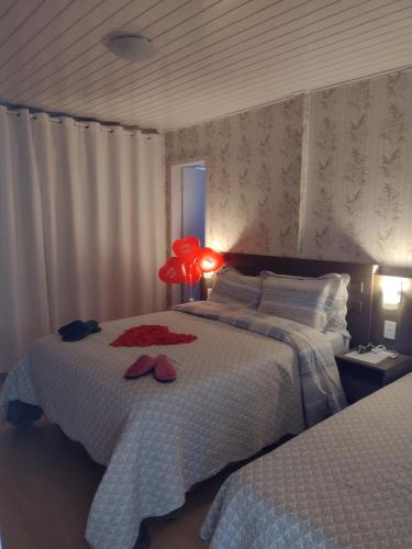 邦雅尔丁-达塞拉Pousada Encantos da Serra的一间卧室设有两张床和红灯