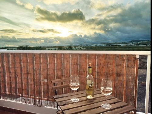 宏达海滩Ámbar的阳台上的一瓶葡萄酒和两杯酒