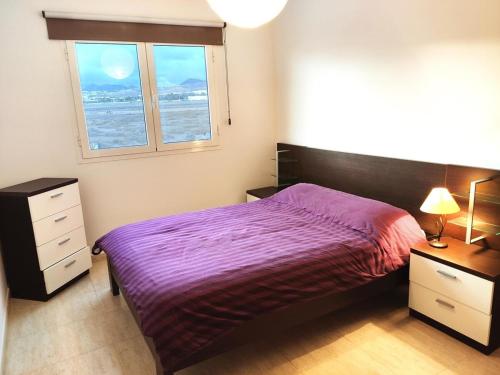 宏达海滩Ámbar的一间卧室设有紫色的床和窗户