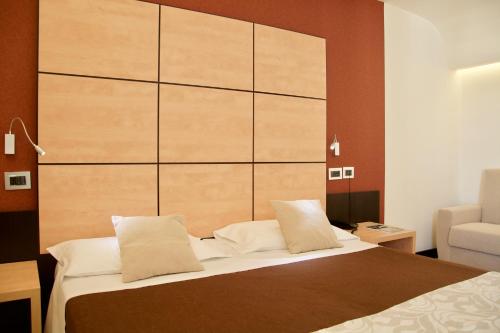 那不勒斯奇玛罗莎酒店的一间卧室配有一张带大型木制床头板的床