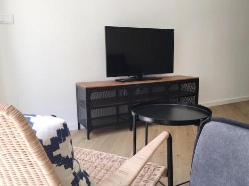 庞特维德拉Casas Á Beira - Apartamentos的客厅配有电视和桌椅