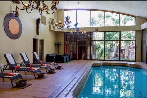 布隆方丹Bloem Spa Hotel & Conference的一个带椅子和大窗户的游泳池