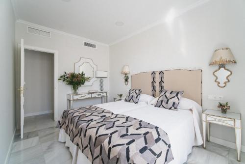 塞维利亚Apartamentos Abreu Suites的白色卧室配有一张带黑白色棉被的床