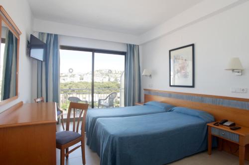 圣蓬萨Hotel Casablanca的配有一张床、一张书桌和一扇窗户的酒店客房