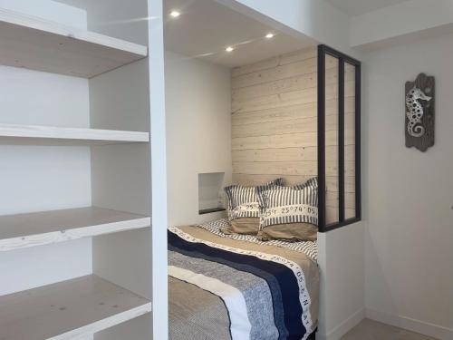 拉弗洛特Le Petit Navire的卧室拥有白色的墙壁,配有带枕头的床铺。