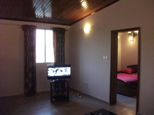 杜阿拉Residence Japoma的带电视的客厅和卧室