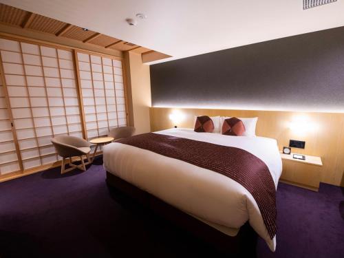 京都Homm Stay Nagi Shijo Kyoto By Banyan Group的酒店客房设有一张大床和窗户。