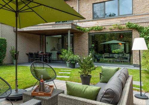 布鲁日Ten Hove Brugge的一个带沙发和遮阳伞的庭院