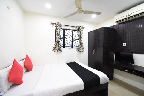 加尔各答鸟巢国际酒店的一间卧室配有一张带红色枕头的床和一扇窗户