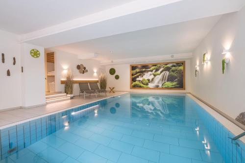 奥伯斯特多夫Hotel garni Gerberhof ***S的一座大型游泳池,铺有蓝色瓷砖地板,配有一张大型绘画作品